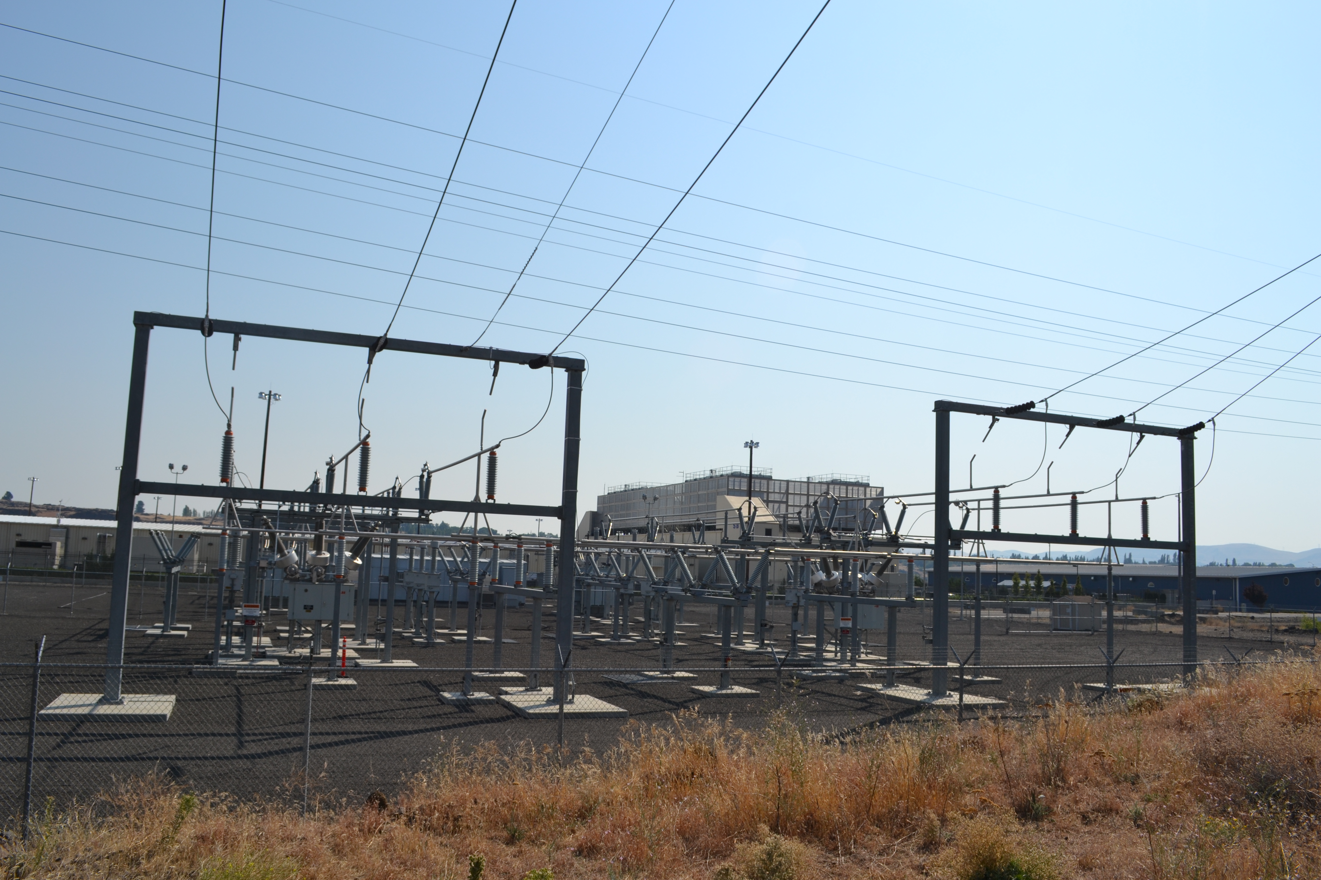 Photorealistic exterior view of a large data centre campus connected to electricity infrastructure.